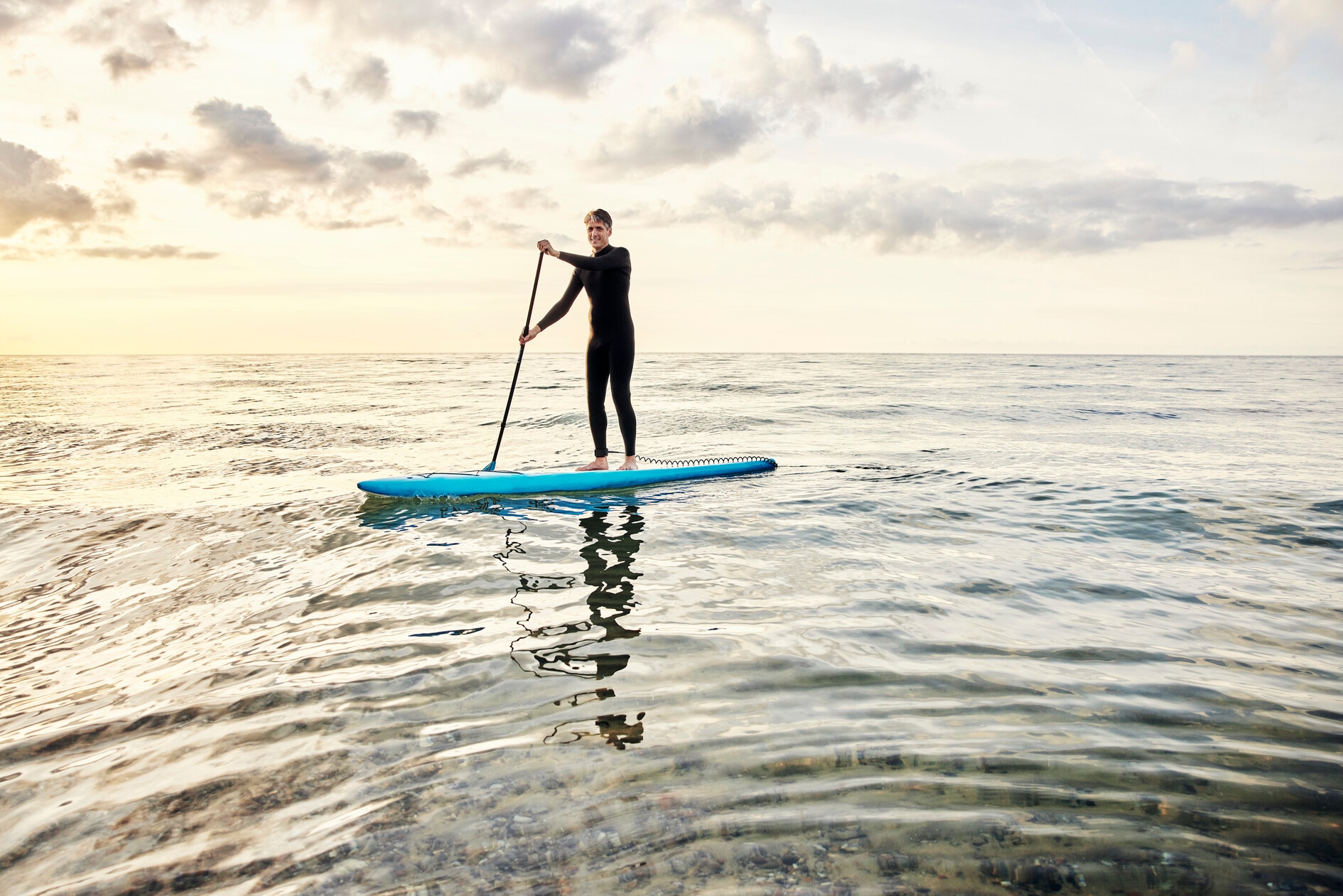 Jürgen, ein Heylo™ Anwender, steht auf seinem Standup-Paddle. Mit Heylo™ können Sie jederzeit schwimmen gehen. Wir empfehlen es Ihnen den Sender vorher zu entfernen.